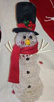 Full view of taller clear acrylic snowman with top hat and red scarf