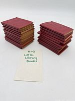 Two stacks of red miniature books showing gilt edges, with lot card