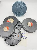Group of canisters and reels showing grey units, one blue, paper labels