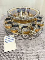 Oblique view of bowl seated in stand with eleven cups displayed