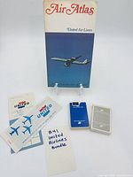 All lot items: Air Atlas map on stand, ticket jacket and receipt, two playing card decks