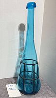 Full view of blue glass bottle in cage