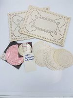 Overall lot showing rectangular placemats, two sealed packages of round doilies, and loose round doilies