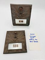 Two vintage metal PO box doors side by side with tag