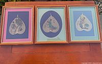 Three framed painted bodhi leaves on bench