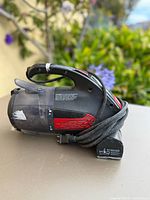 Left side view of Dirt Devil handheld vacuum showing dust cup, handle, vent detail and cord