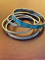 Stacked view of one wide turquoise inlay bangle with three narrow silver-tone inlay bangles