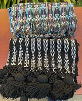 Folded rebozo showing multicoloured centre and black-white ikat end with pom-pom fringe