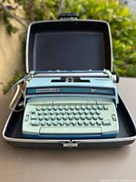 Typewriter seated in open case, full view of keyboard and carriage