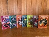 Seven Star Trek Voyager DVD box sets seasons 1-7 lined up on wooden surface