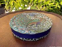 Top view of round box with peacock design and text