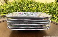 Side view of stacked square floral plates showing red edged rims