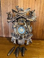 Front view of carved cuckoo clock showing carvings, dial, weights