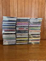 Front view of three stacks of vintage music CDs on wood surface