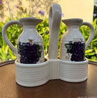 Two ceramic cruets with grape decals in white caddy, front view