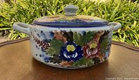 Front view of round ceramic casserole with lid showing floral pattern and side handles