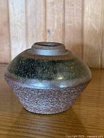 Front view of squat stoneware vase showing glazed shoulder and textured body