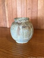 Front view of rounded stoneware vase showing glaze and incised petal motif