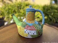 Front view showing sunflower motif, spout, lid and handle