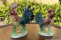 Front view of both Phoenix chicken figurines on wooden surface