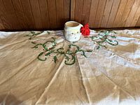 Santa mug centered on embroidered holly tablecloth