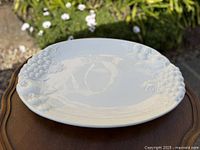 Top view of white ceramic platter showing grape relief