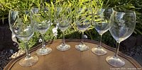 Six etched wine glasses grouped outdoors, frontal angle