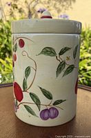 Side view of ceramic cookie jar showing hand painted fruit motif