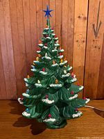 Full view of assembled 24" ceramic Christmas tree, lights inserted, star on top, base visible