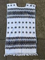 Full front view of white tunic with black embroidery and fringe