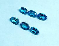 Six oval blue topaz gemstones on white background