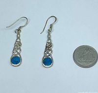 Full view of both earrings alongside coin for scale