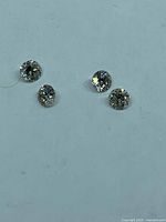 Four loose round diamonds on light background