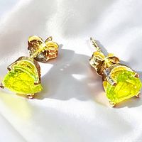 Close-up of both heart-shaped peridot stud earrings showing stone color and gold setting