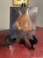 Front view of brushed copper boxer dog plaque on stand showing relief detail and signature area