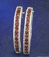 Front view of both sterling silver hoop earrings showing red gemstone rows