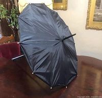 Parasol side view open on table showing canopy and shaft