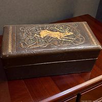 Closed leather box on table showing Art Nouveau stag design on lid
