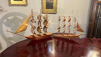 Both carved wooden sailboats on table