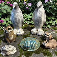 Group of two cement birds, resin raccoons, cement frog, ceramic sun dish