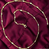 Full view of necklace laid on fabric showing chain, beads, clasp