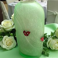 Front view of light green frosted glass vase with red appliqués and silver-tone rim