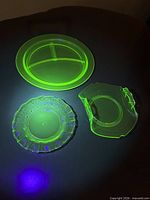 Three uranium glass pieces glowing under UV light