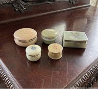 Five alabaster boxes displayed on wood surface