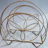 Oblique view of brass wire stand showing atomic starburst pattern and base slots