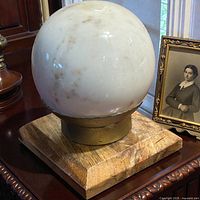 Marble sphere on brass collar and wood base, front view