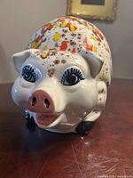 Front view of ceramic piggy bank showing face, coin slot and paint detail