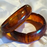 Pair of translucent root-beer brown Bakelite bangles resting on fabric