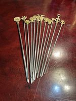 All 12 skewers fanned to show brass finials and steel shafts