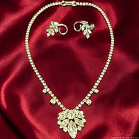 full view of necklace and earrings on red fabric